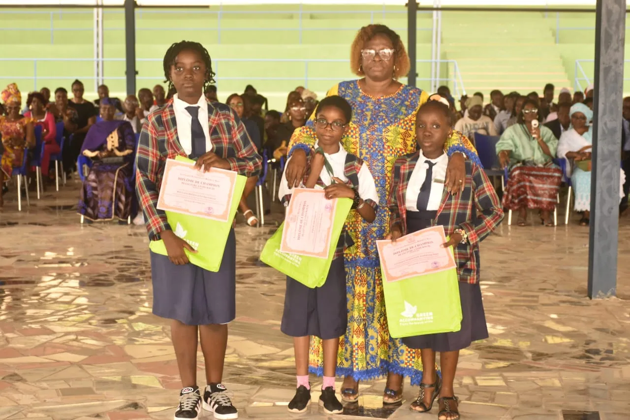 Trois élèves présentant leurs diplômes et leurs prix avec une membre de l’équipe éducative